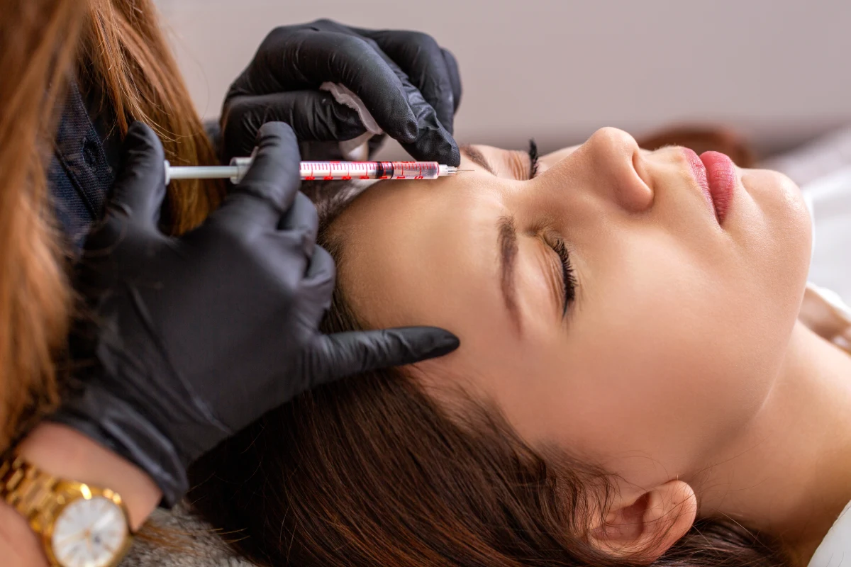 Woman receiving an injectable treatment near her forehead to address expression wrinkles with Botox and Dysport at Reflections Medspa & Wellness Center